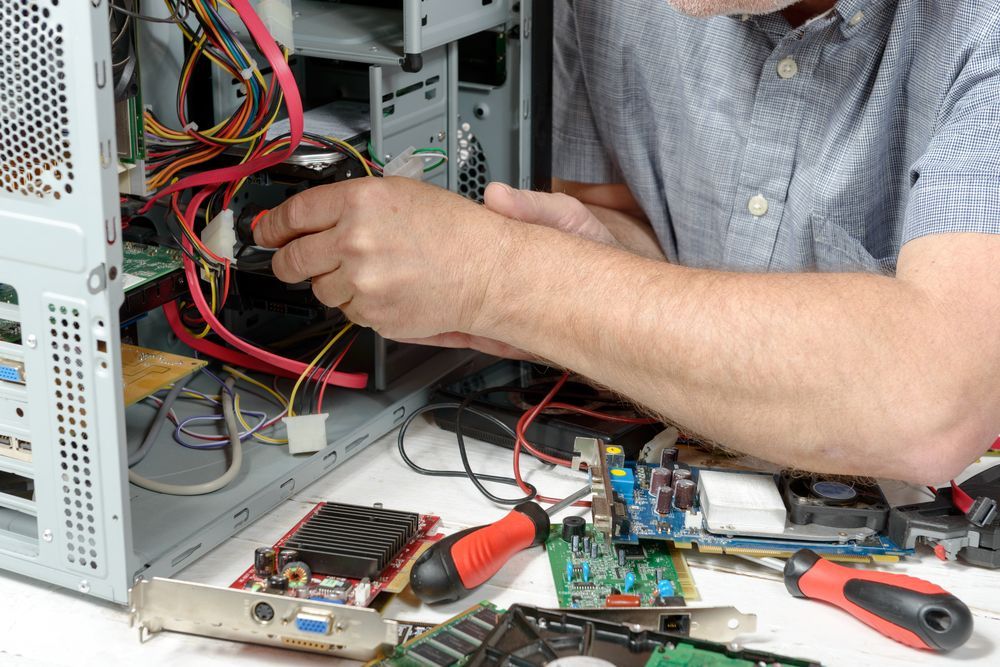 A Man Is Working On A Computer With A Screwdriver — Dateline Computers Authorised Jaycar Reseller In Airlie Beach, QLD