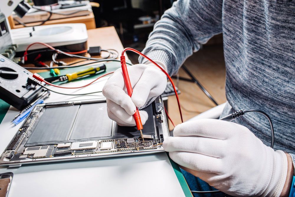 A Man Wearing White Gloves is Working on a Laptop Computer — Dateline Computers Authorised Jaycar Reseller In Airlie Beach, QLD