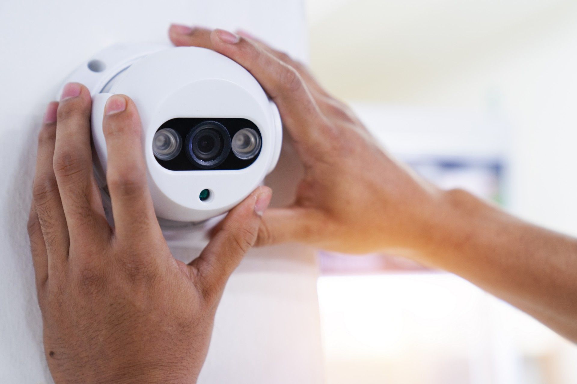 Una persona sta installando una telecamera di sicurezza su un muro.