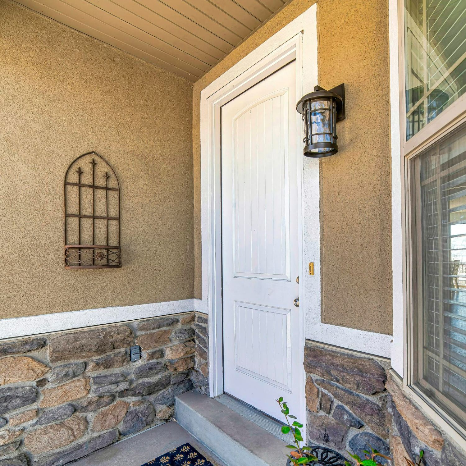 A white door is sitting on a porch next to a stone wall.
