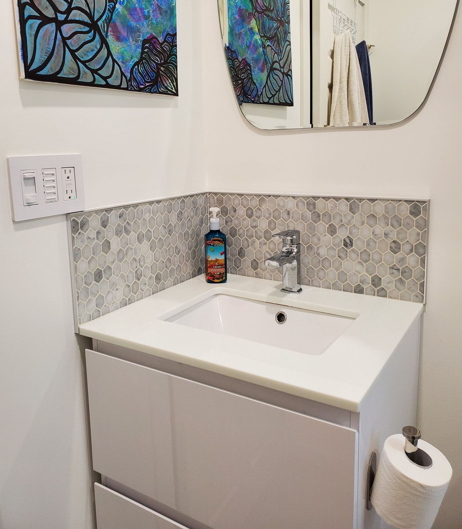 A bathroom with a sink , mirror and paintings on the wall.