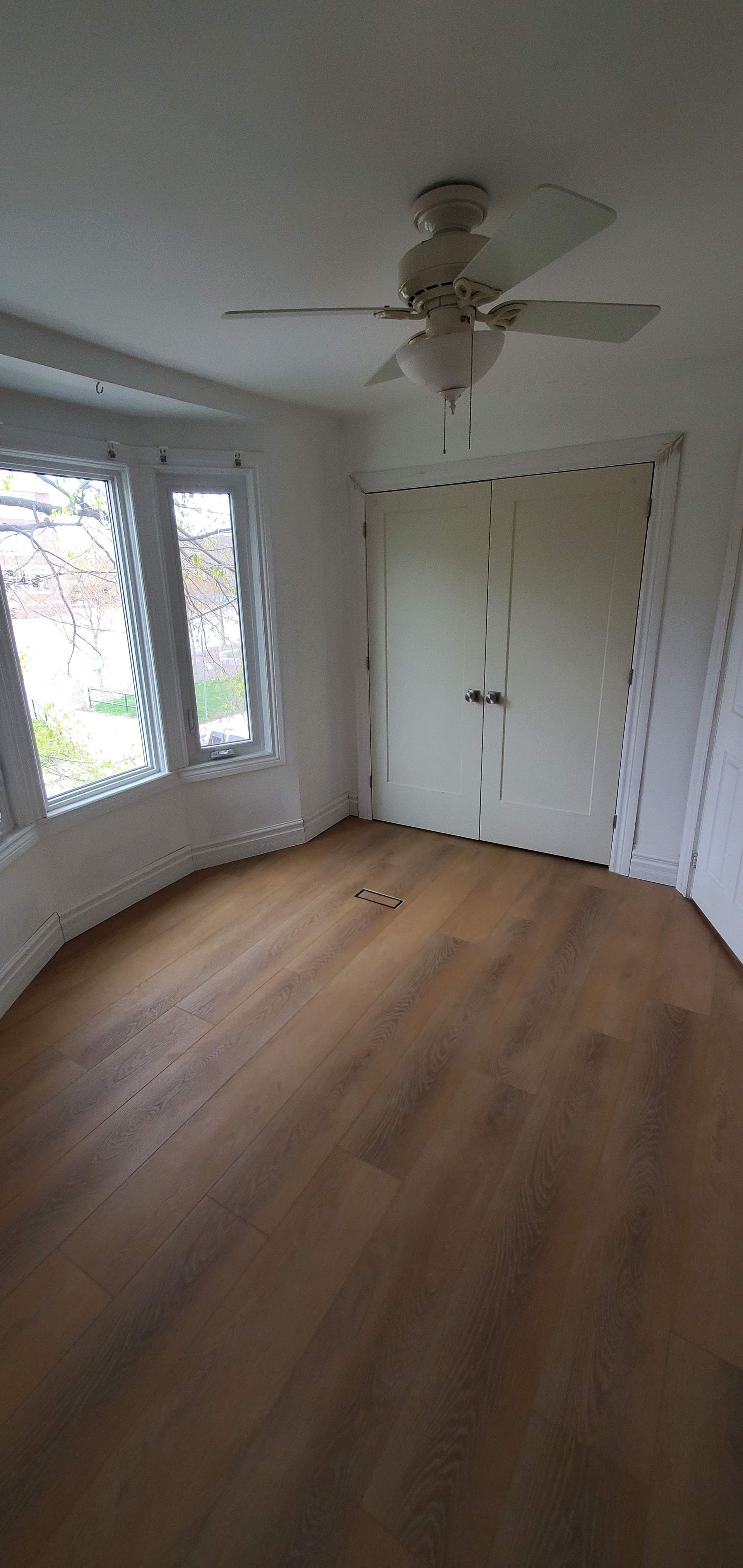 An empty room with hardwood floors and a ceiling fan.