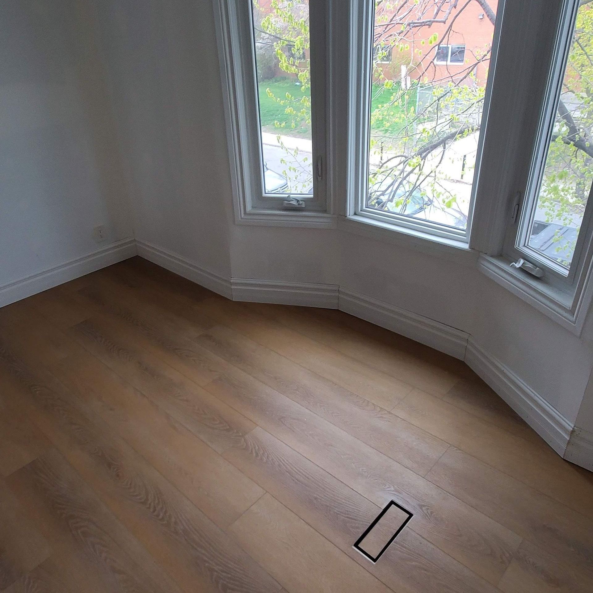 A room with a wooden floor and a large window.