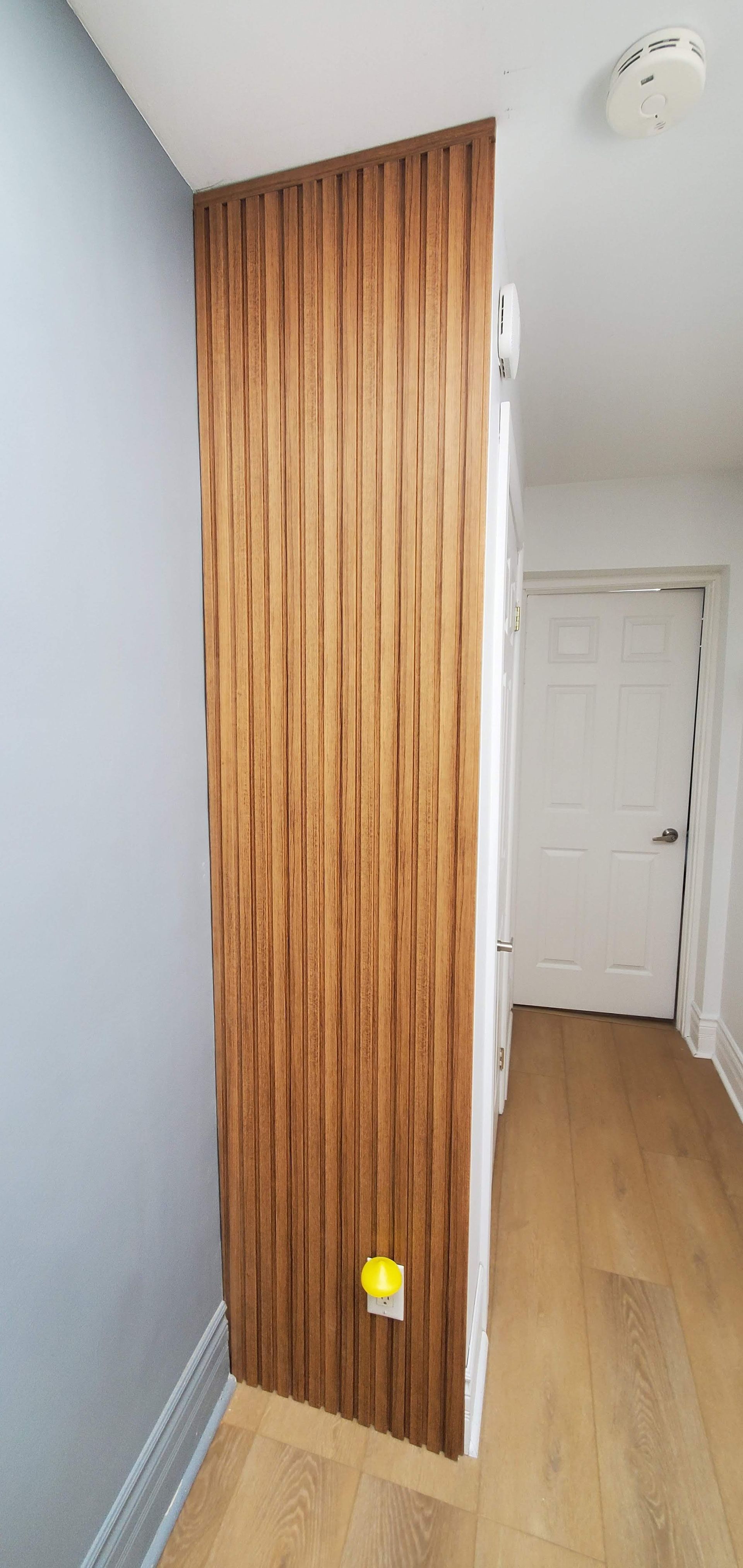 A hallway with a wooden wall and a door.