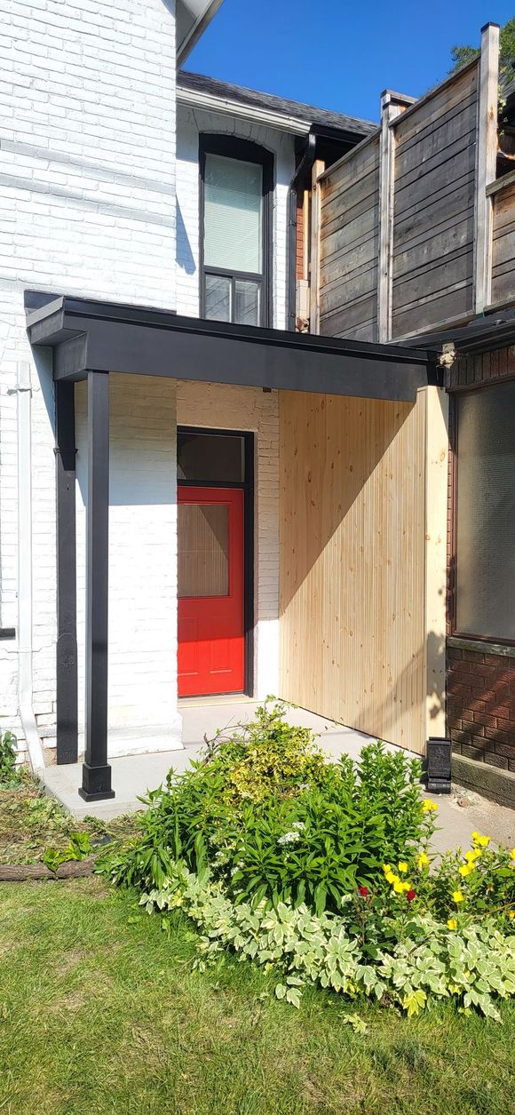 A white house with a red door and a wooden porch.