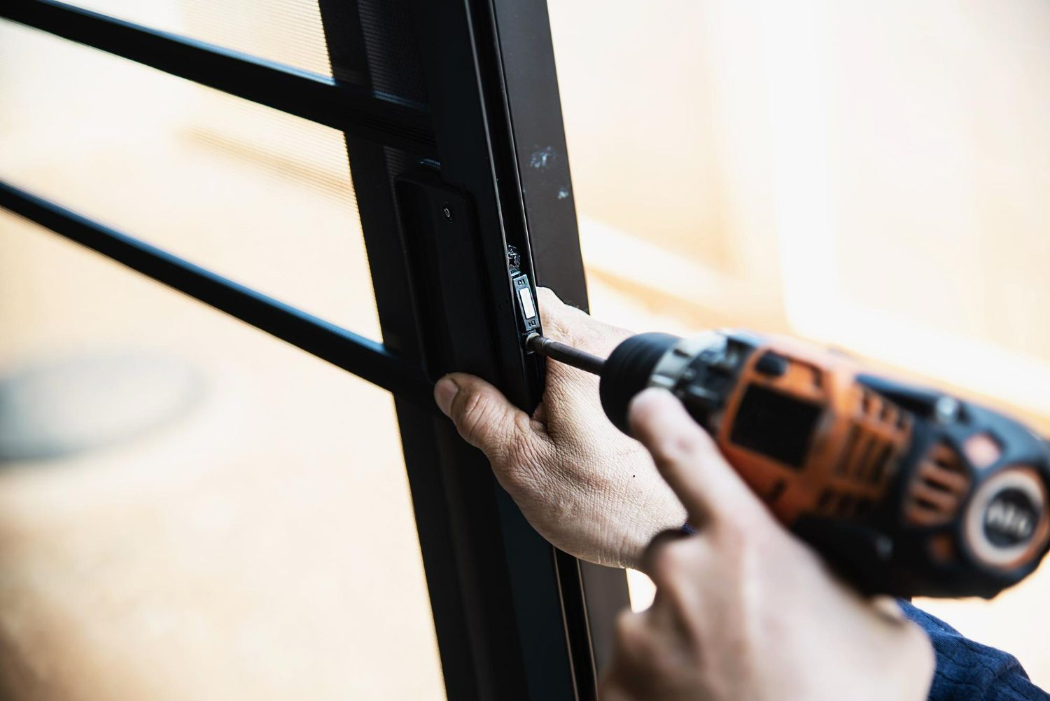 A person is using a drill to fix a door.