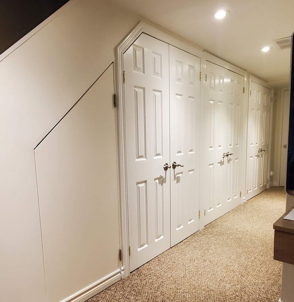 Hallway with multiple white storage doors, sloped ceiling, and carpeted floor.