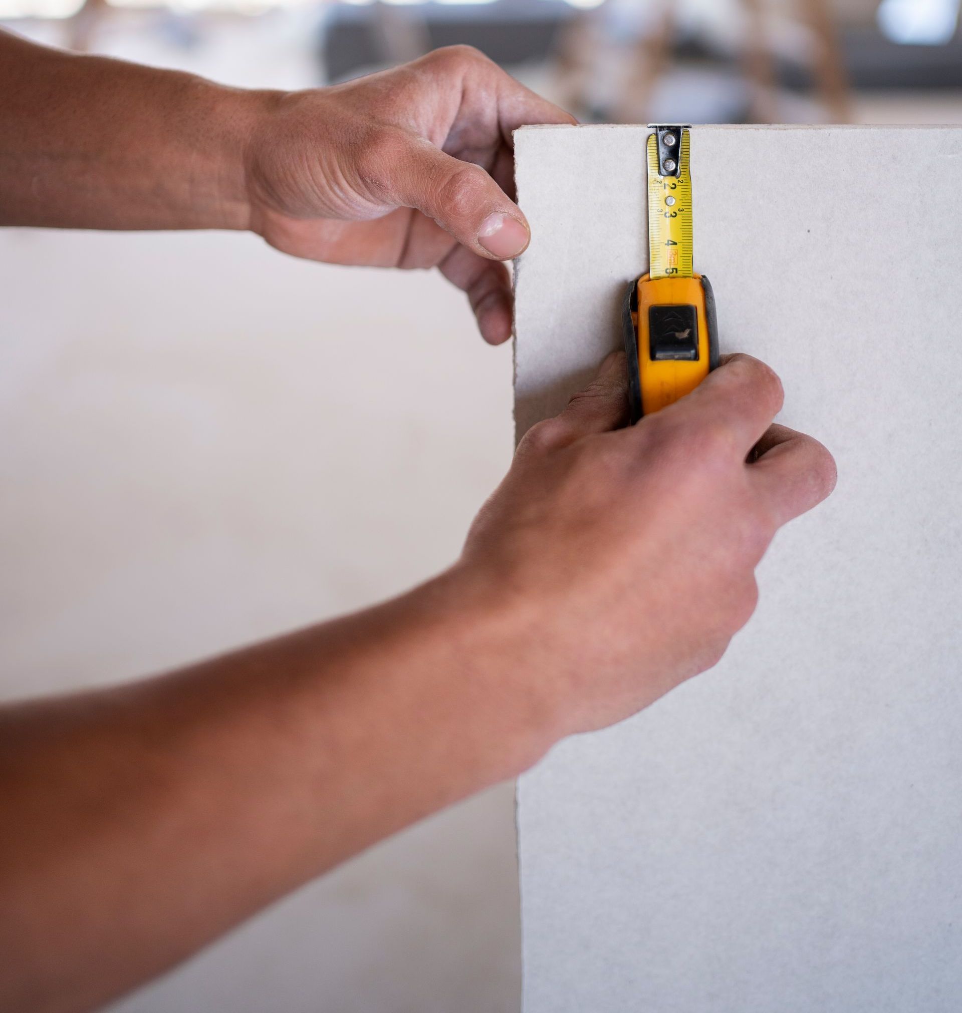 A person is measuring a wall with a tape measure for a feature wall