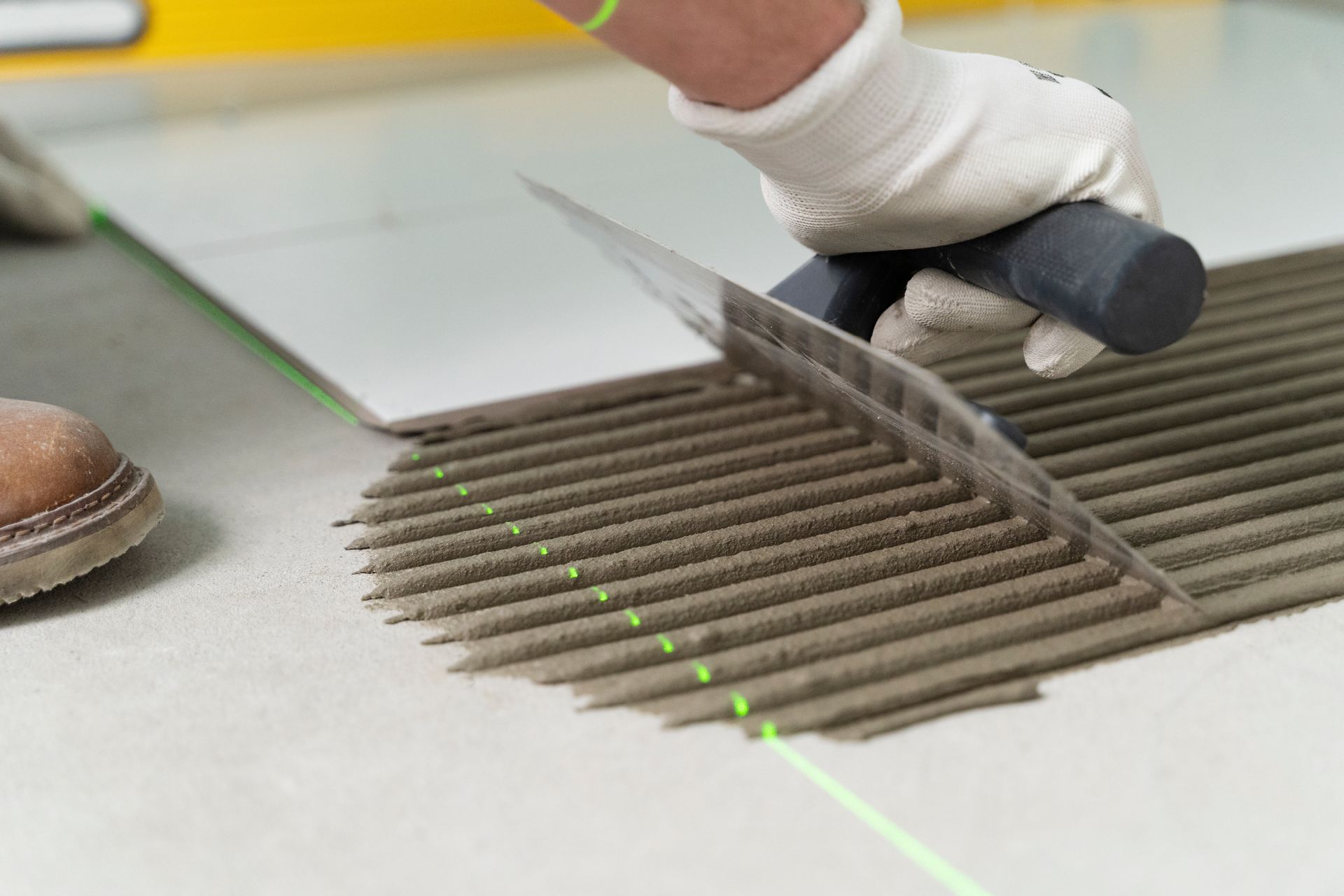 A person is laying tiles on the floor with a trowel.
