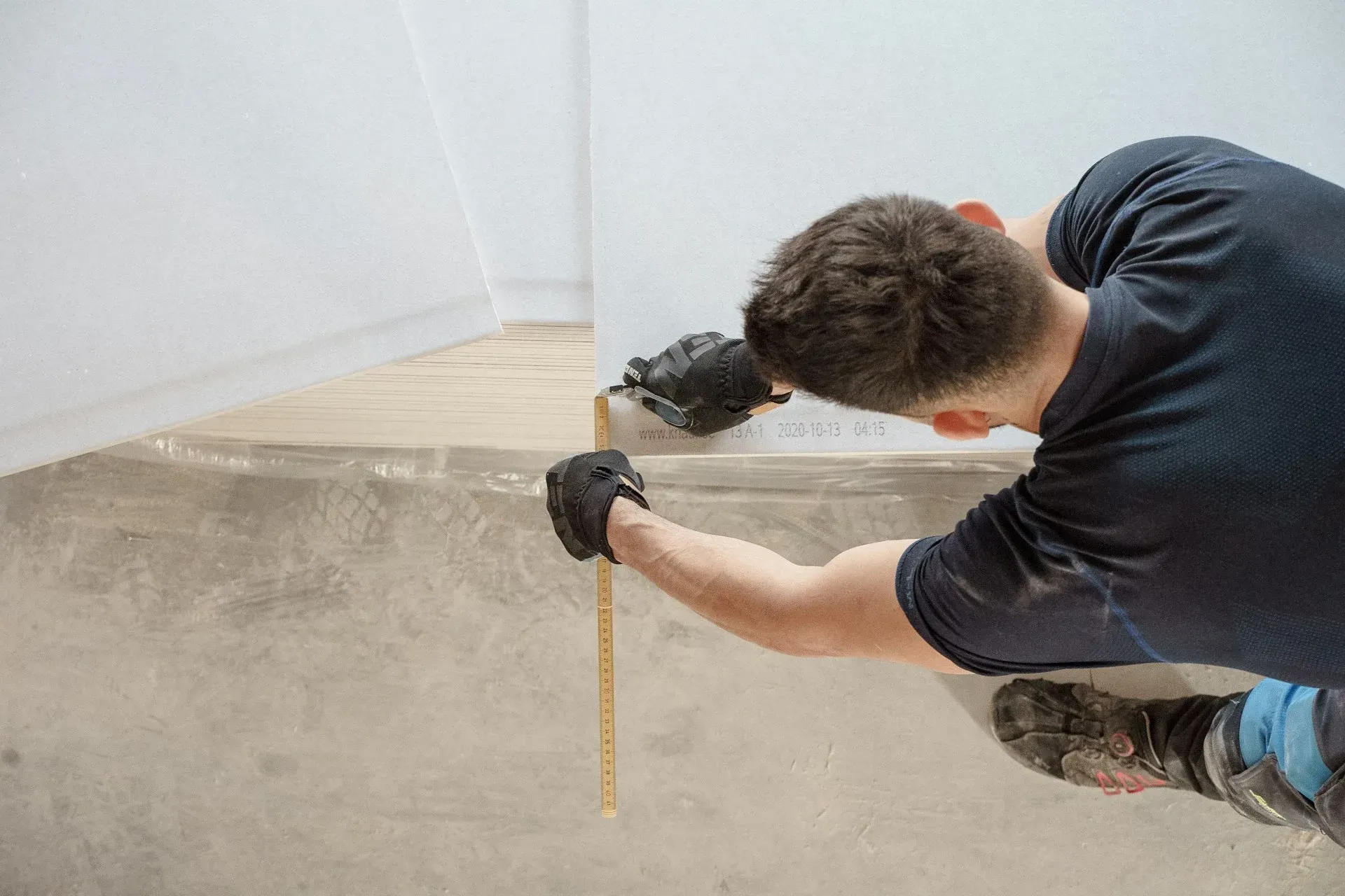 Worker measuring a sloped concrete surface with a tape measure and power tool outdoors