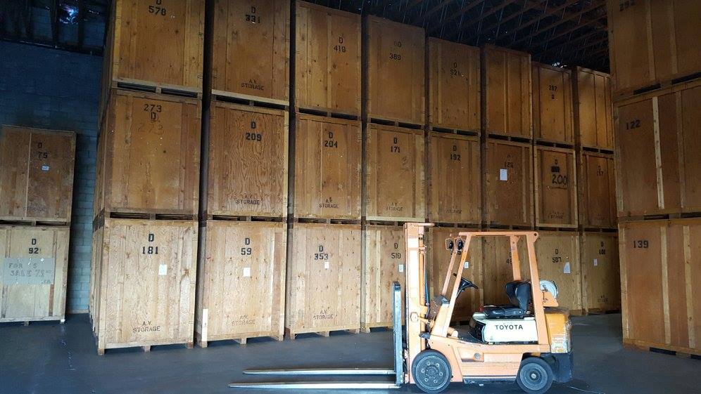 Forklift in a warehouse stacked with wooden crates.