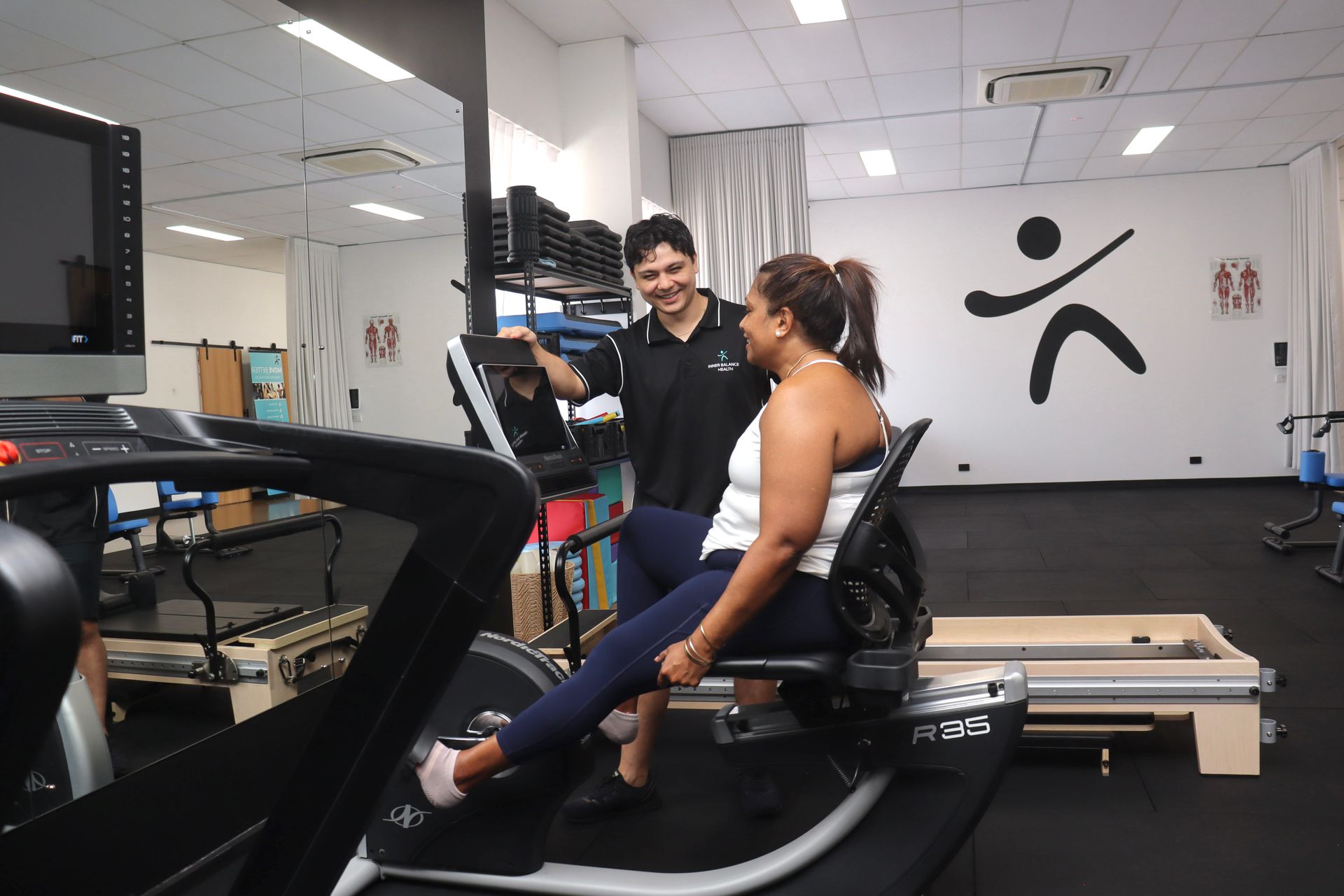 A Physical Therapist Assists a Client Using a Recumbent Exercise — Inner Balance Health in Coconut Grove, NT