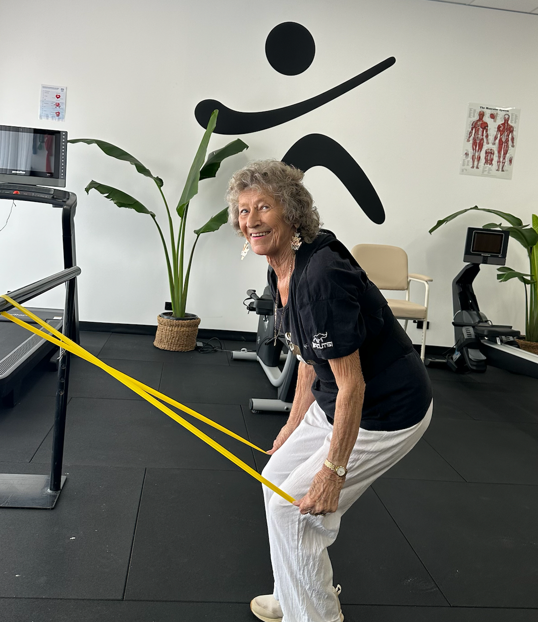 A Person Smiles While Exercising With a Yellow Resistance Band — Inner Balance Health in Coconut Grove, NT
