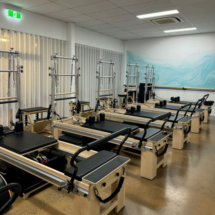 A rOom With Rows of Light Wood Pilates Reformers and Towers — Inner Balance Health in Coconut Grove, NT