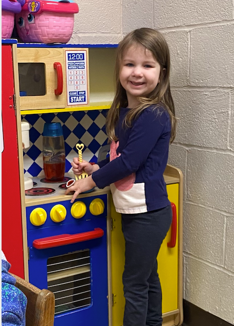 A little girl playing on a fake cooking station.