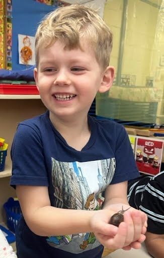 A young boy is sitting at a table with a rainbow made out of paper.