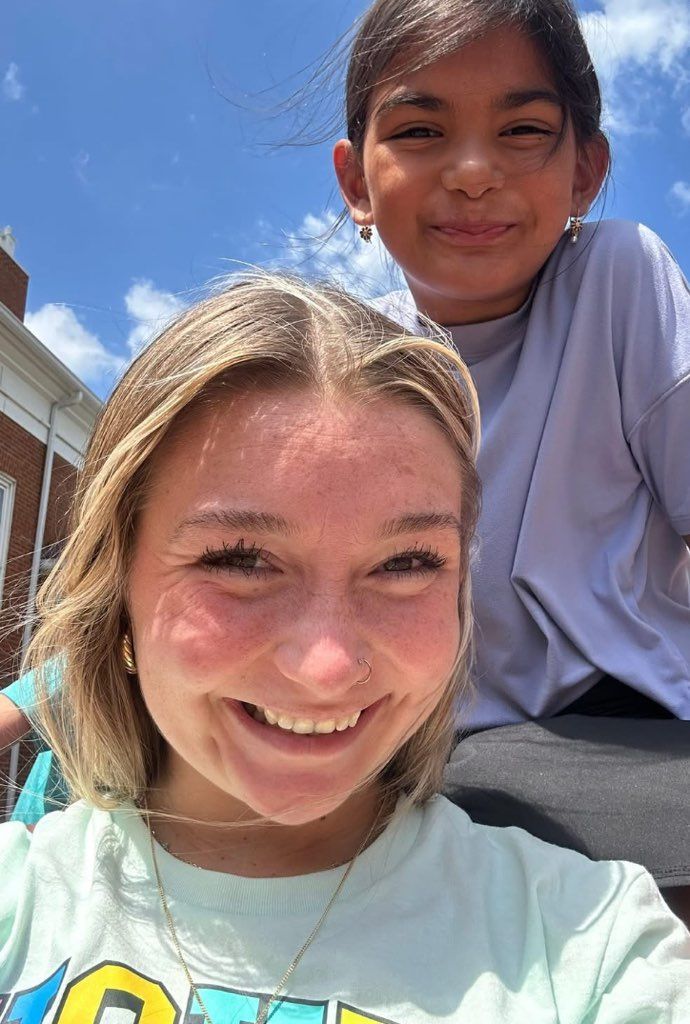 Two young girls are posing for a picture together and smiling.