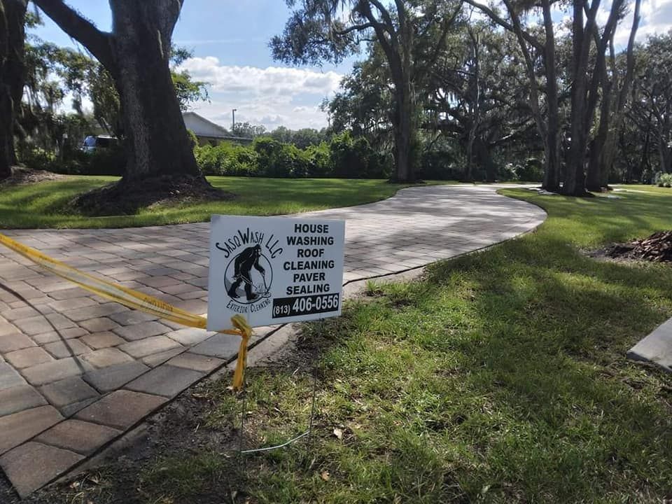A sign is sitting in the grass next to a brick walkway.