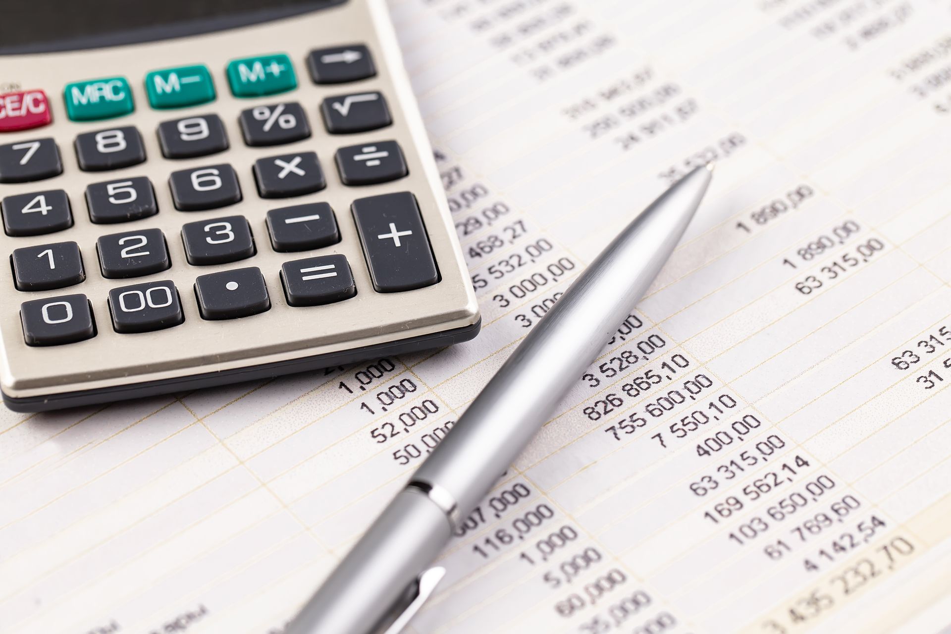 Calculator, pen, and financial document with numerical data.
