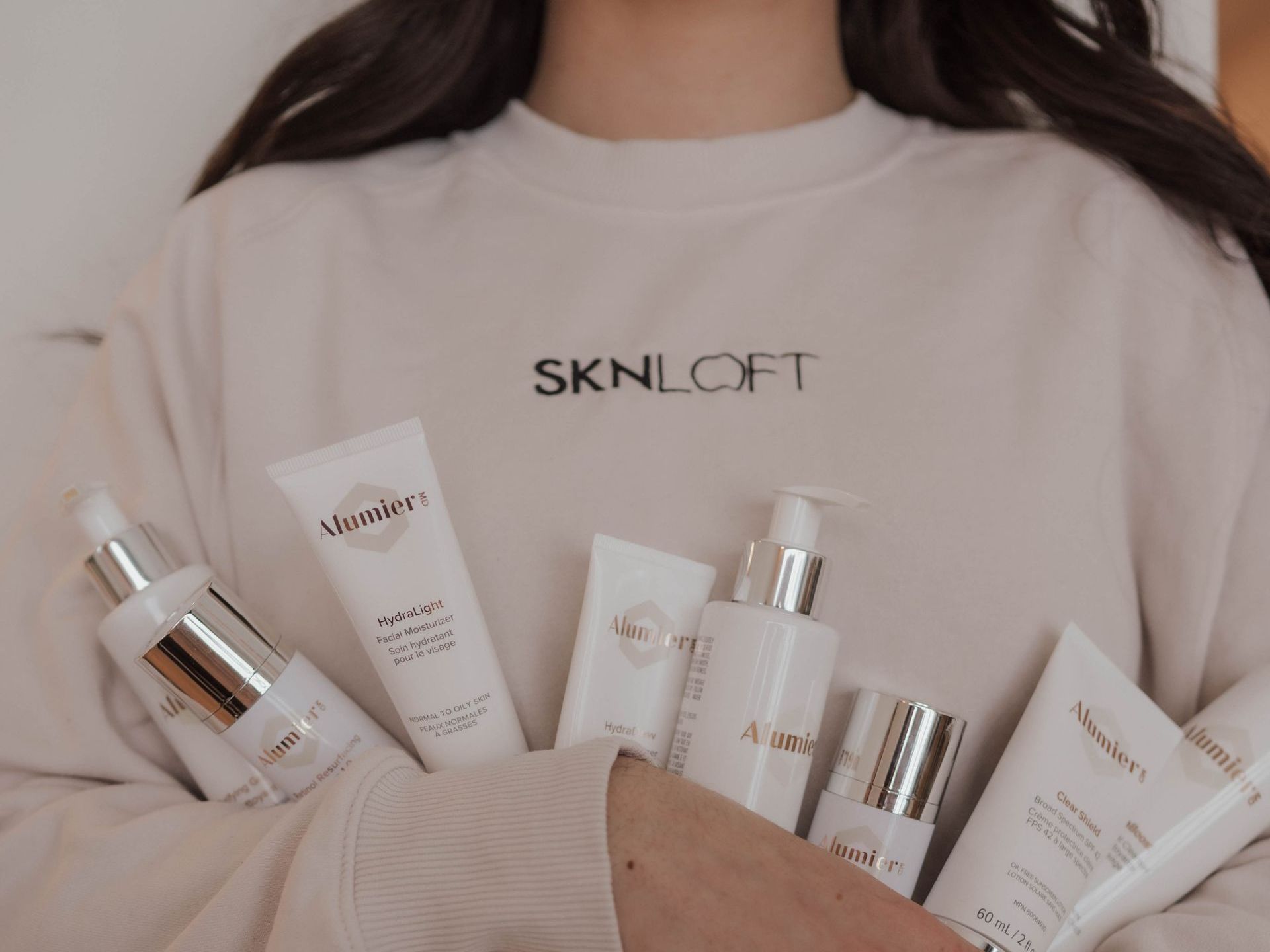 A woman wearing a sweater that says ' skinloft ' on it