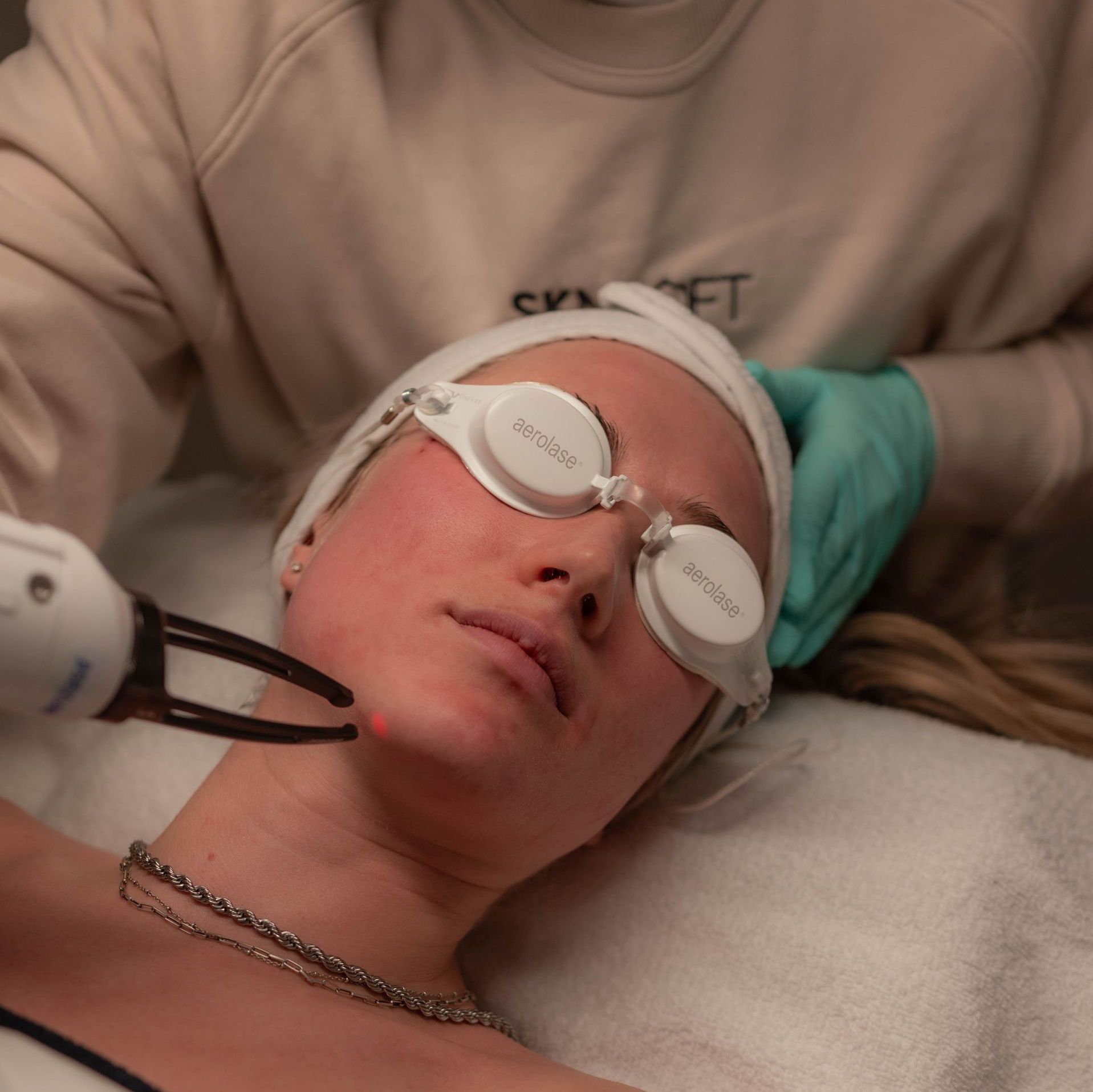Person receiving a facial treatment with protective eye covers and a handheld device in a spa setting