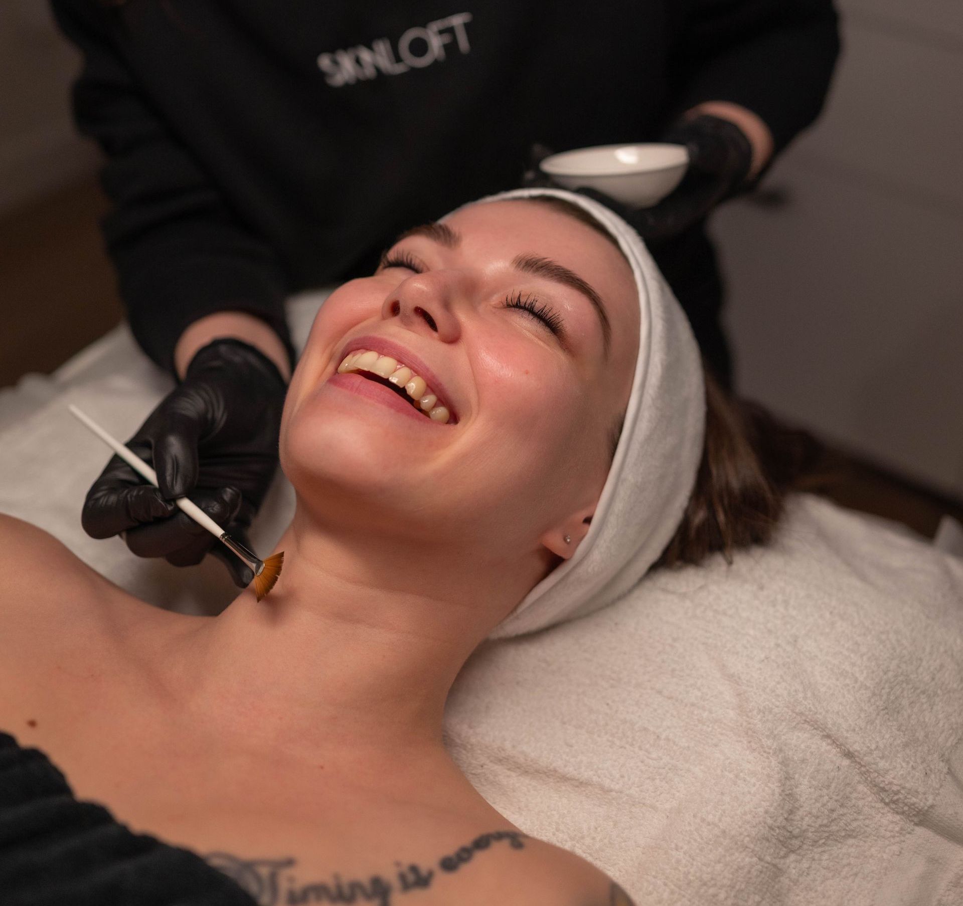 Woman receiving a facial treatment while smiling on a spa bed