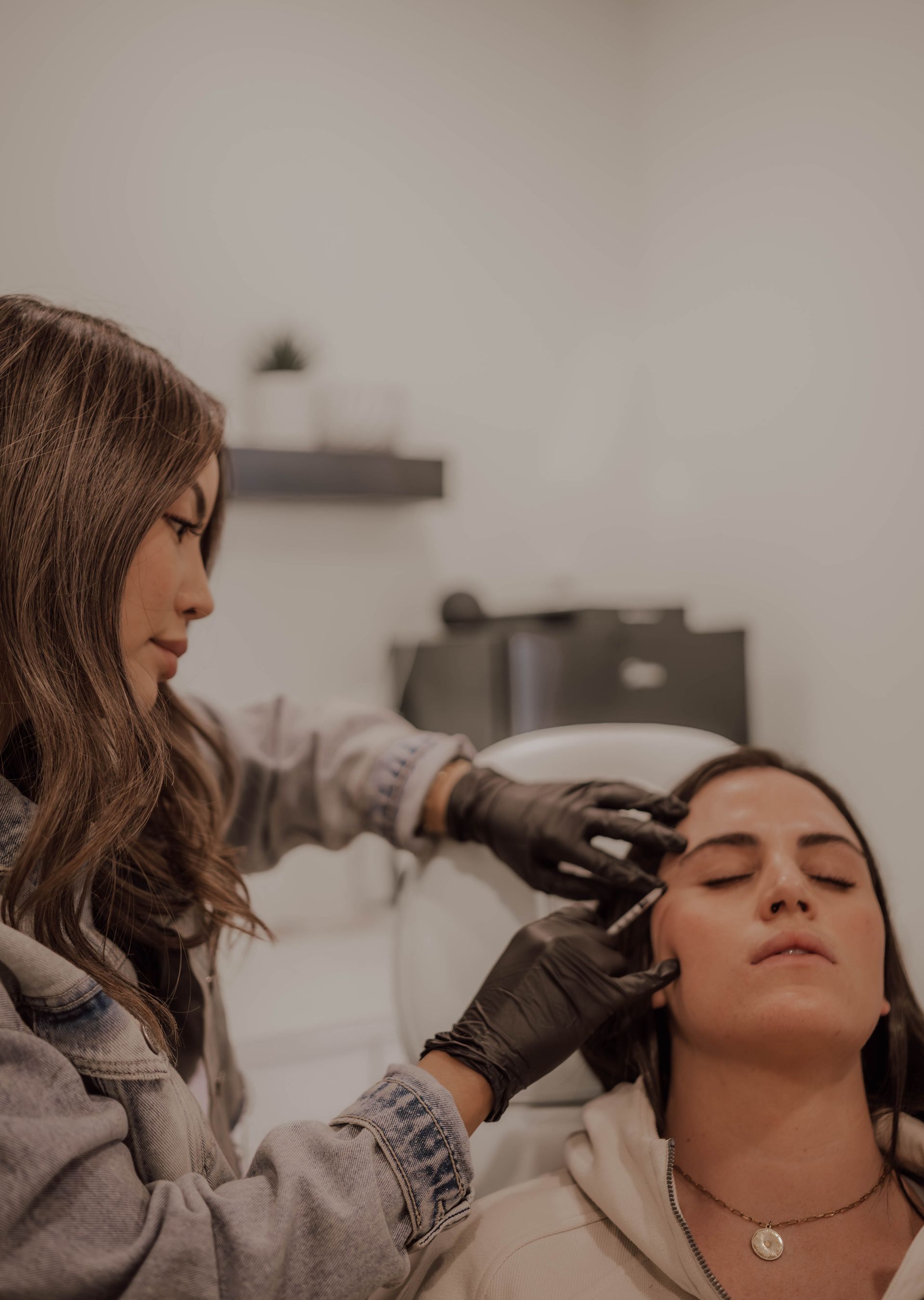 Aesthetician applying facial treatment to a reclining client in a spa setting