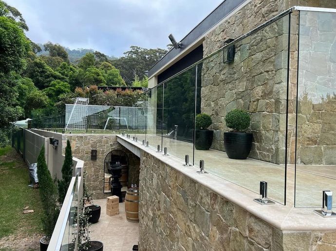 A Large Stone Building with a Glass Railing on the Side of It — Bulli Glass in Bulli, NSW