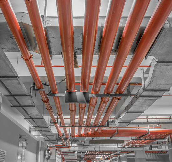 Red pipes run across a concrete ceiling, likely for fire suppression or plumbing.