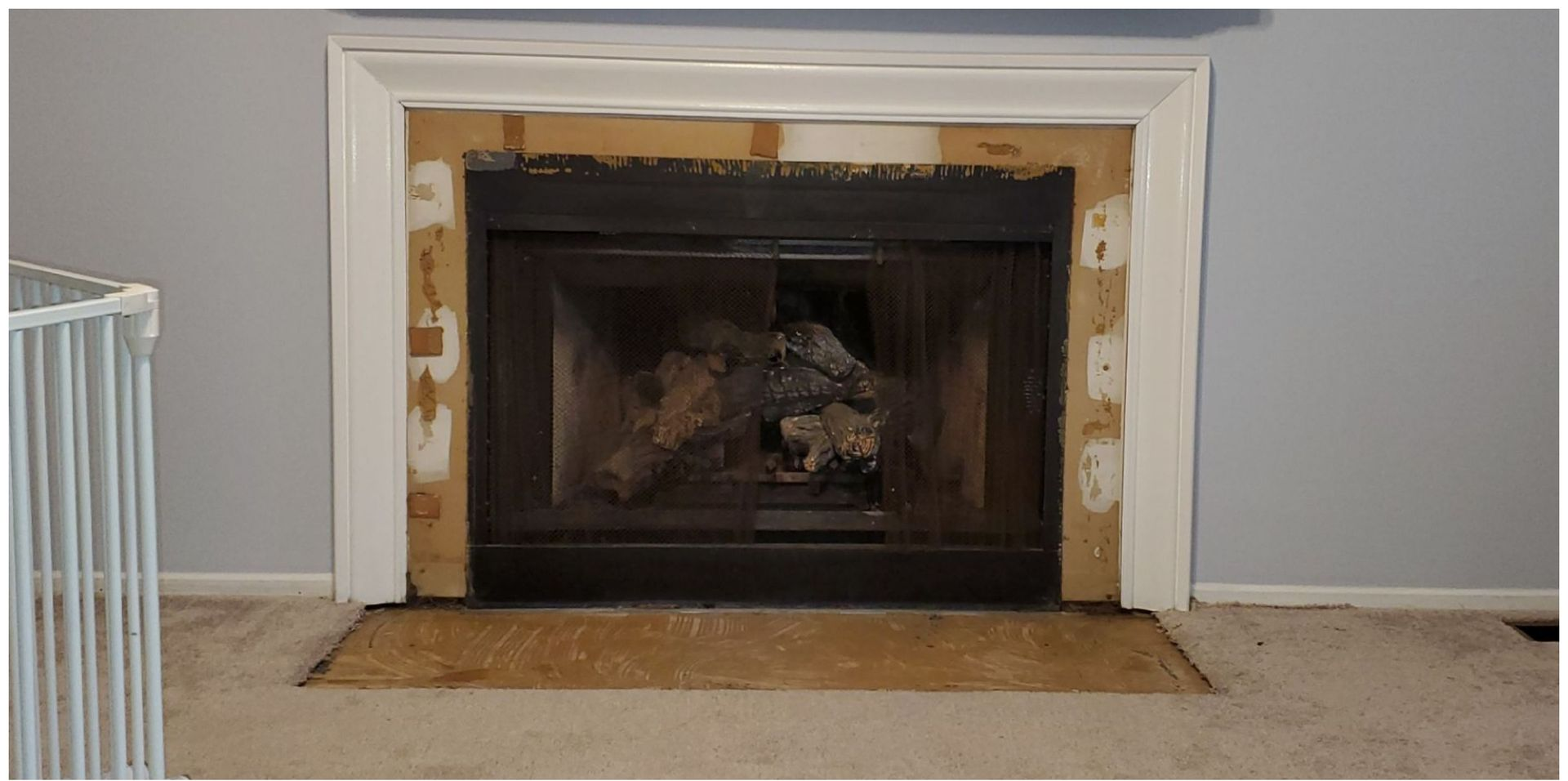 White fireplace mantel with dark insert and a tan hearth against a gray wall
