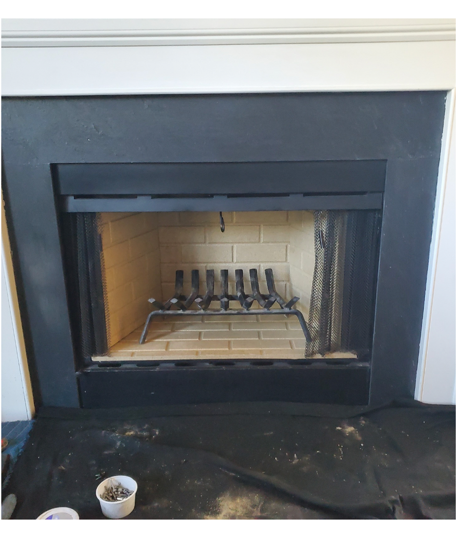 Dark fireplace with black mantel and brass fireplace tools inside