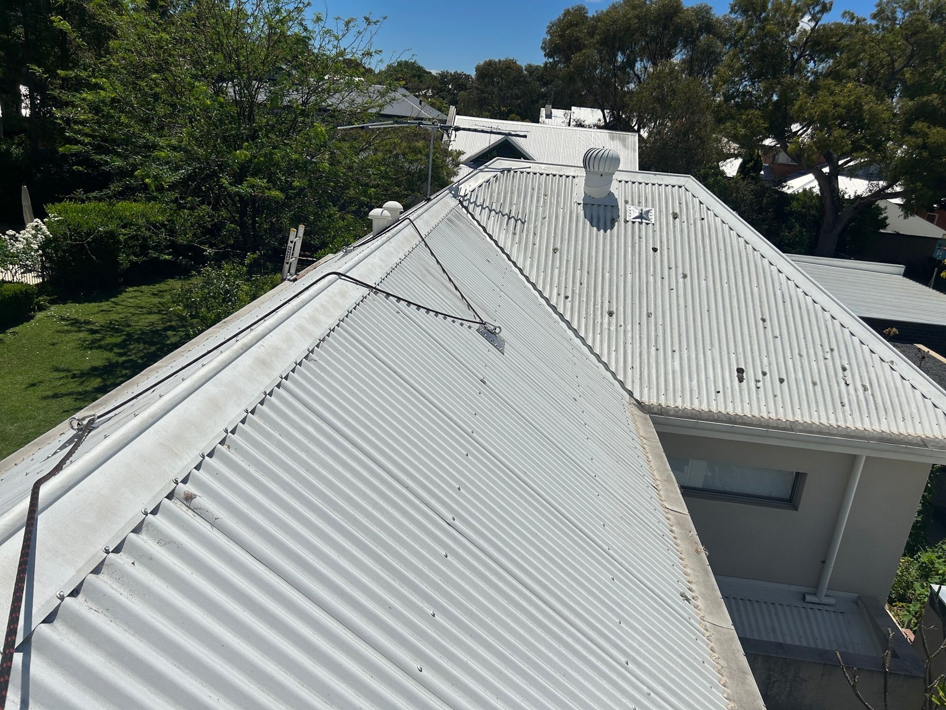 An aerial view of a white roof of a house with trees in the background.
