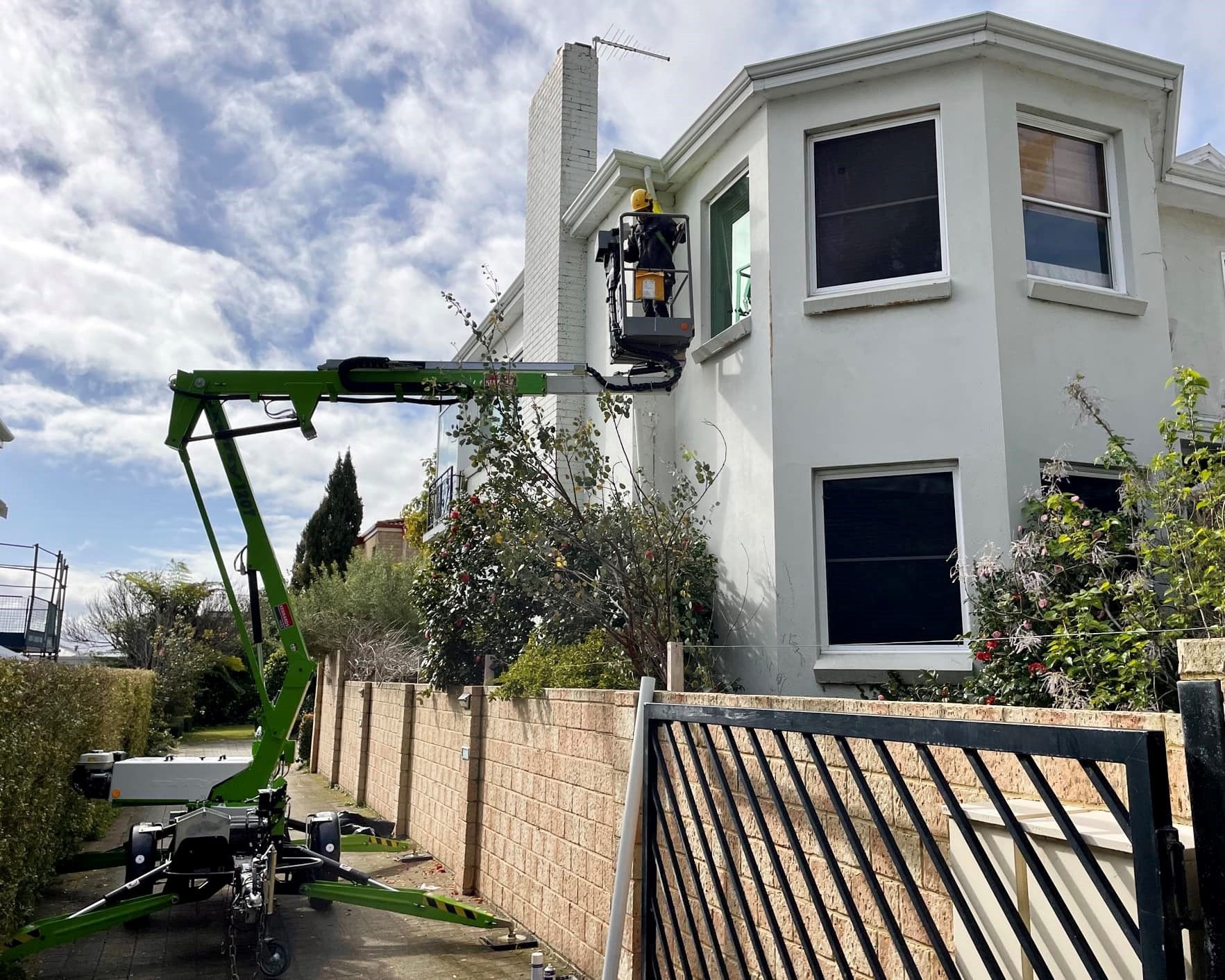 a green crane is sitting in front of a white house .