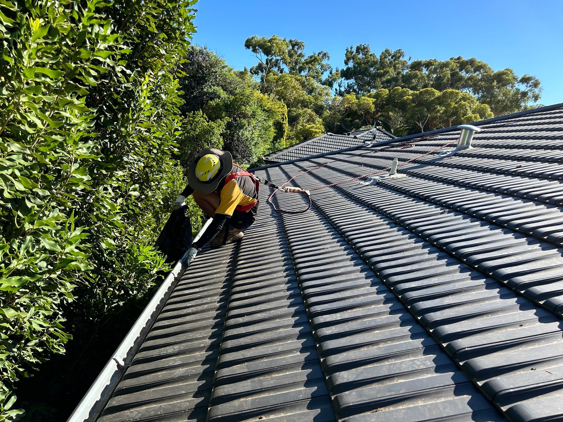 A man is climbing up the roof of a house.