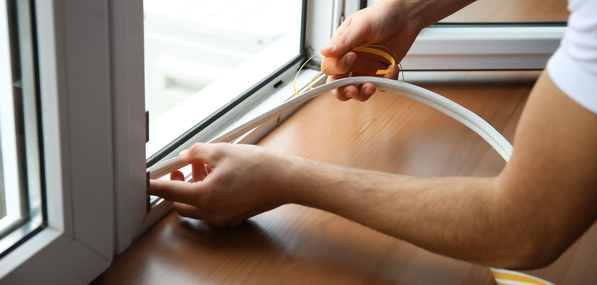 Person installing window weather stripping with scissors.