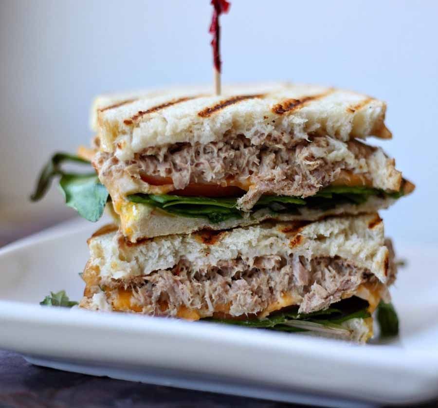 A tuna sandwich is stacked on top of each other on a white plate.