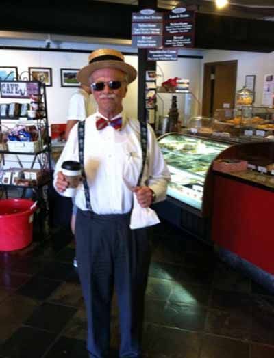 A man wearing suspenders and a hat is holding a cup of coffee