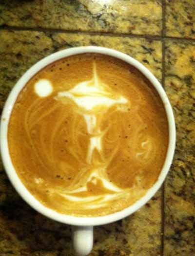 A cup of coffee with a drawing of jesus on the foam