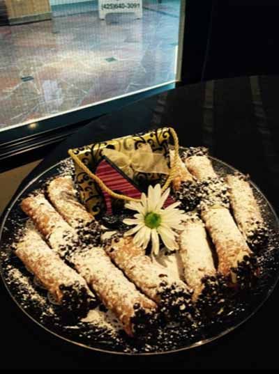 A plate of cannoli with powdered sugar and a flower on top