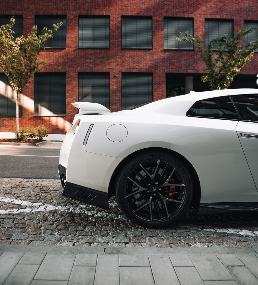 White sports car parked on cobblestone street near a brick building.