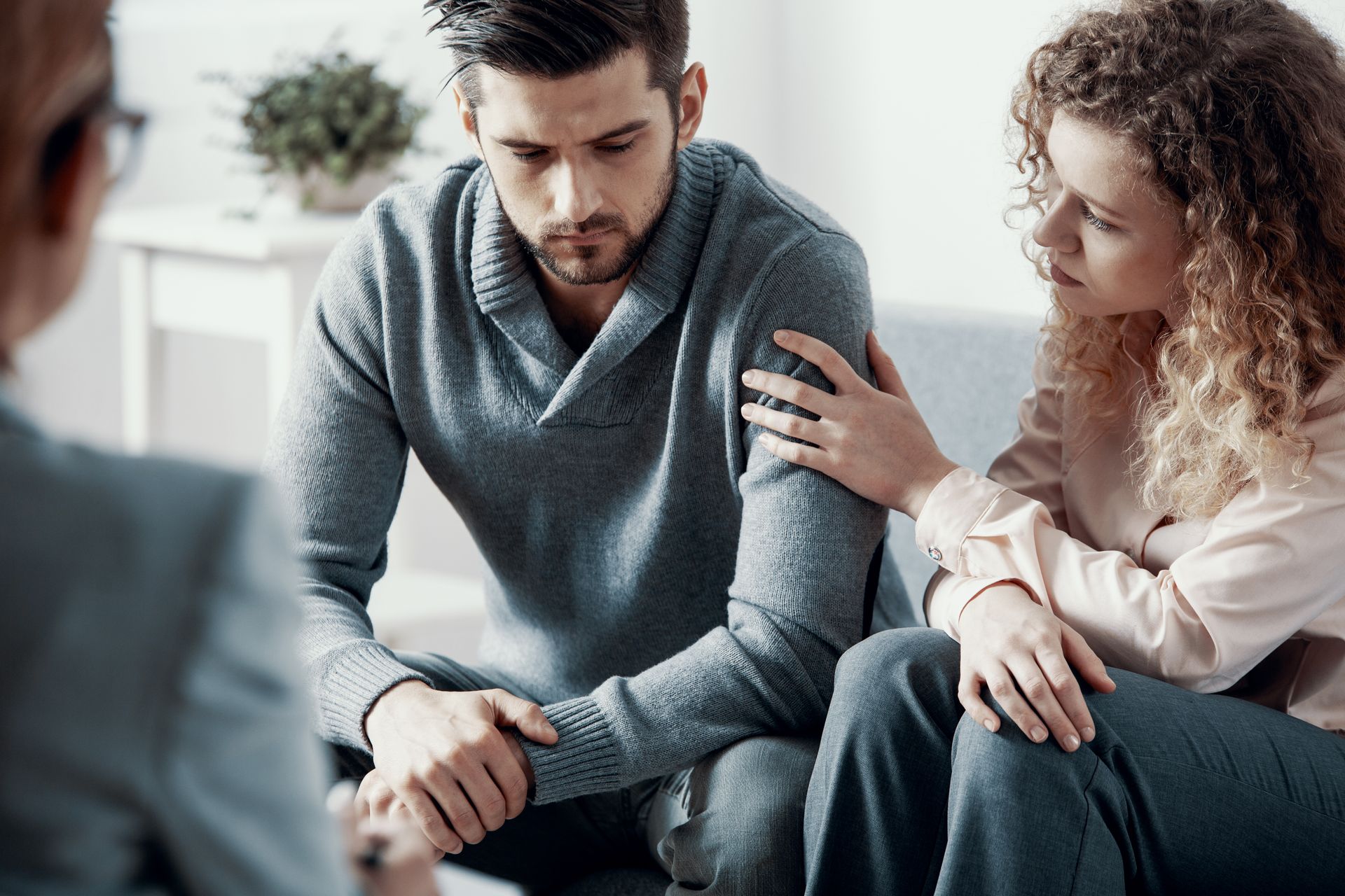 A man and a woman are sitting on a couch talking to a counselor.