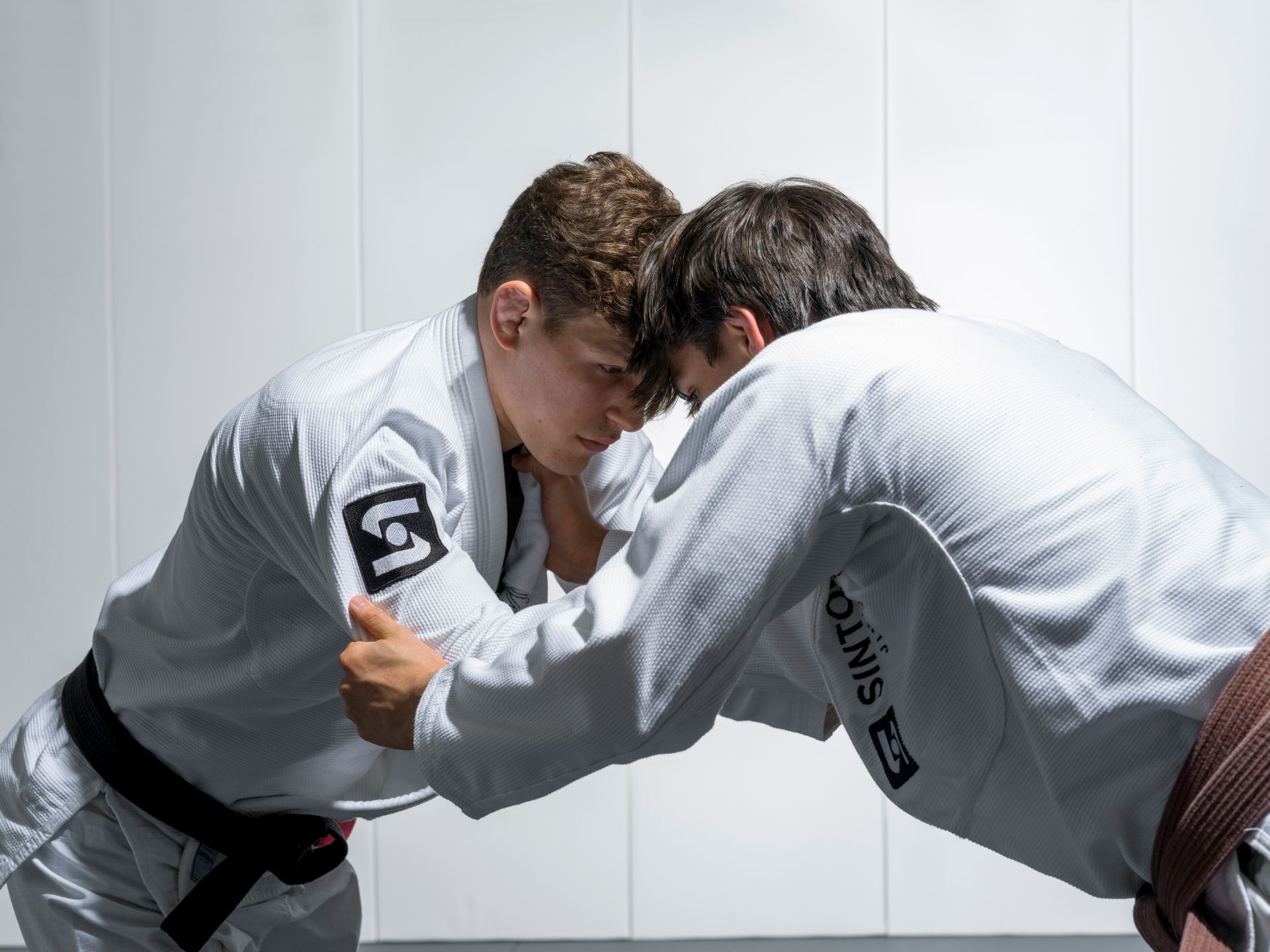 Two grapplers grip fighting in gis at Sintonia Jiu Jitsu, New York