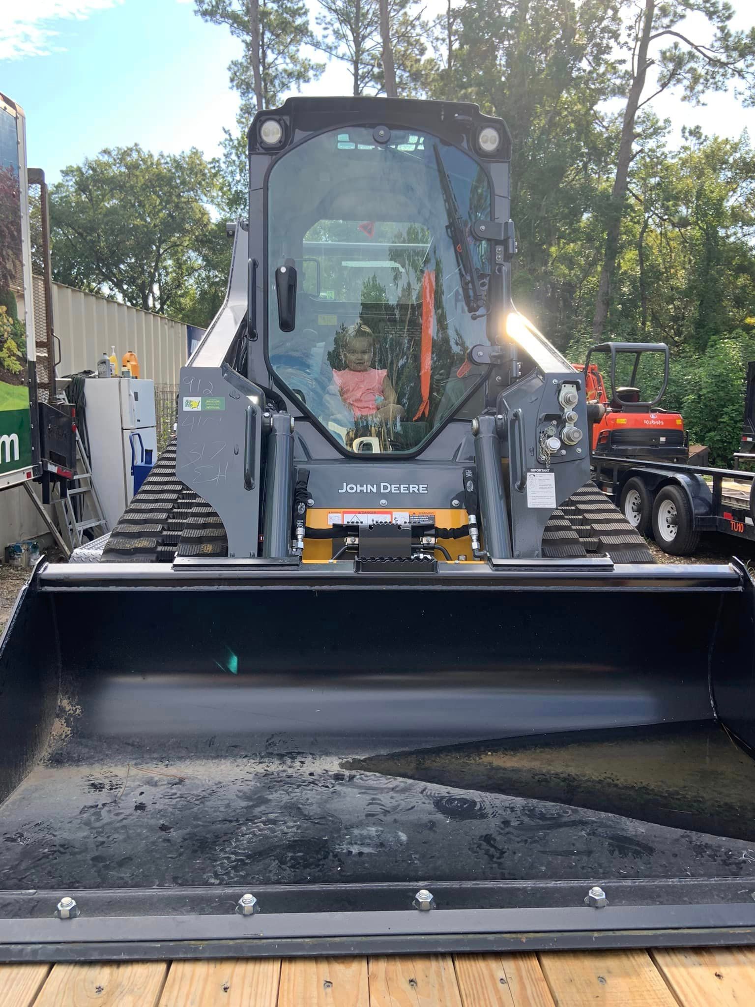 Yellow front-end loader with a wide black bucket parked outdoors on a street.