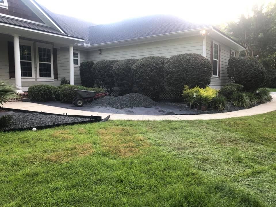 Front yard of a house with green lawn, shrubs, and a curved concrete walkway.