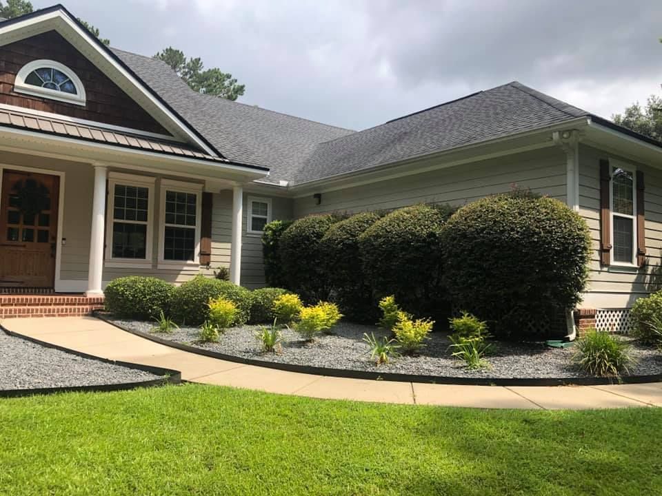 Suburban house with a front porch, curved walkway, manicured shrubs, and green lawn
