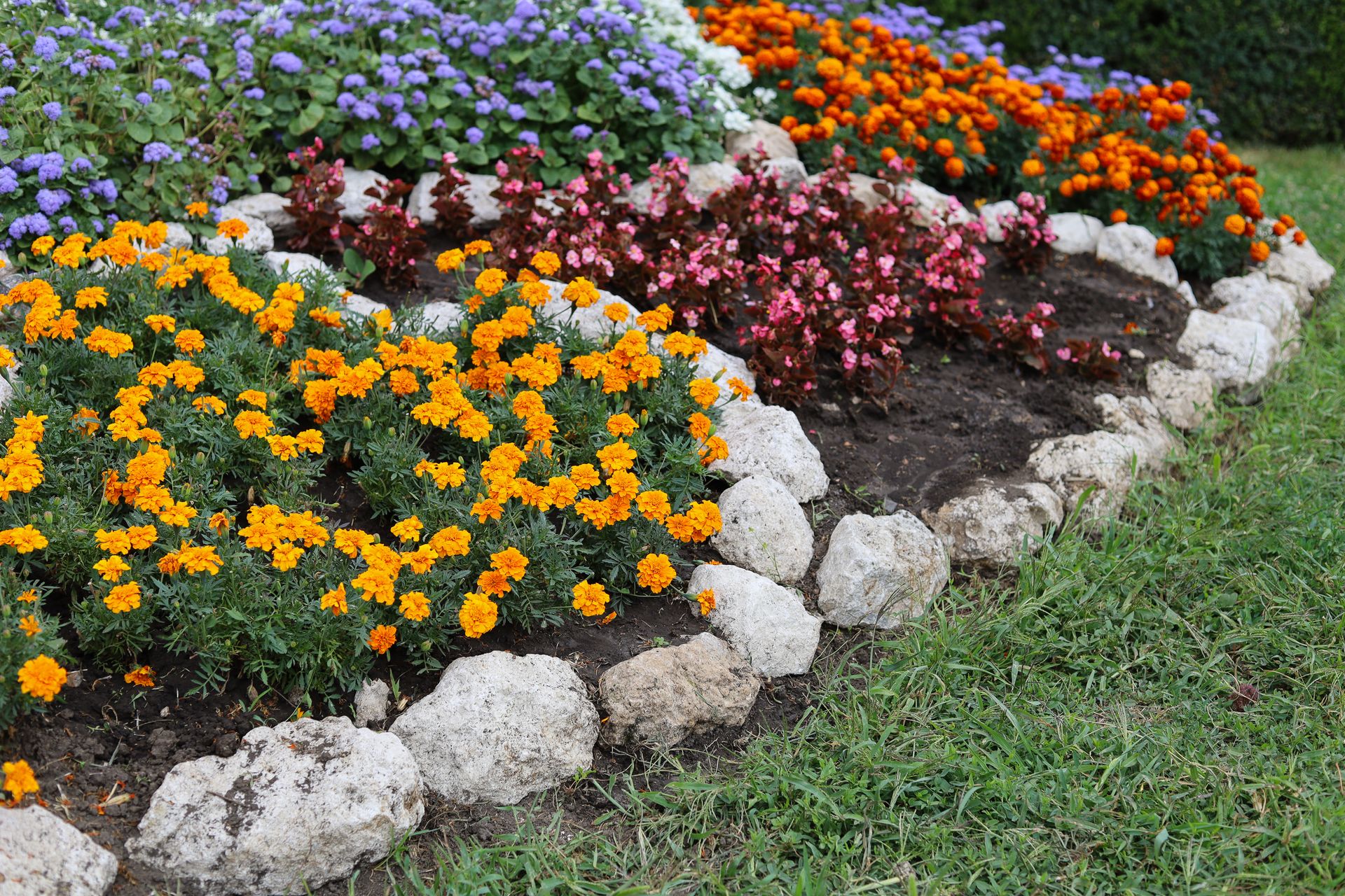 Colorful flower bed bordered with white rocks along a grassy edge