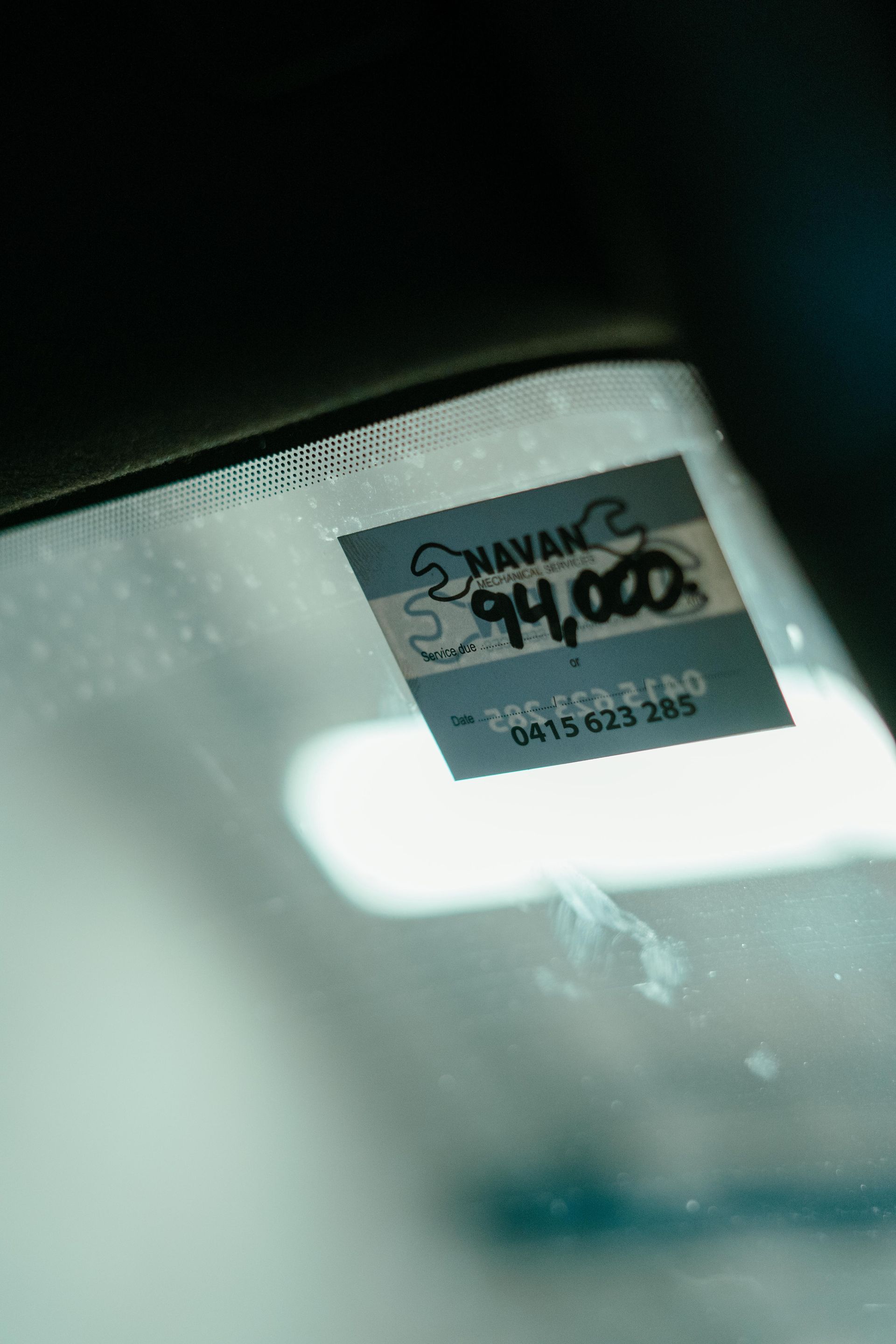 Close-up of a car windshield with a sticker showing the word