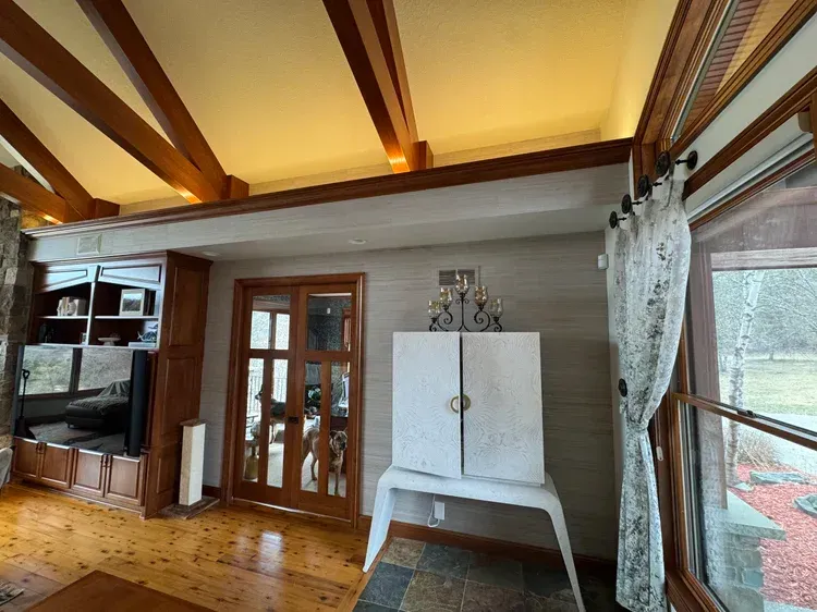 A living room featuring vaulted wooden ceilings, a built-in wooden shelving unit, French doors, and a white storage cabinet.