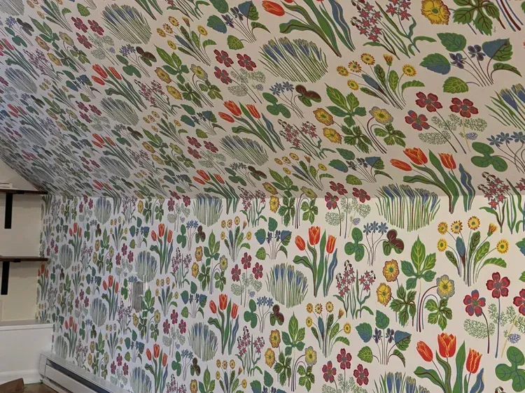 Wallpaper featuring a dense, colorful pattern of various flowers, clovers, and plants on a white background.