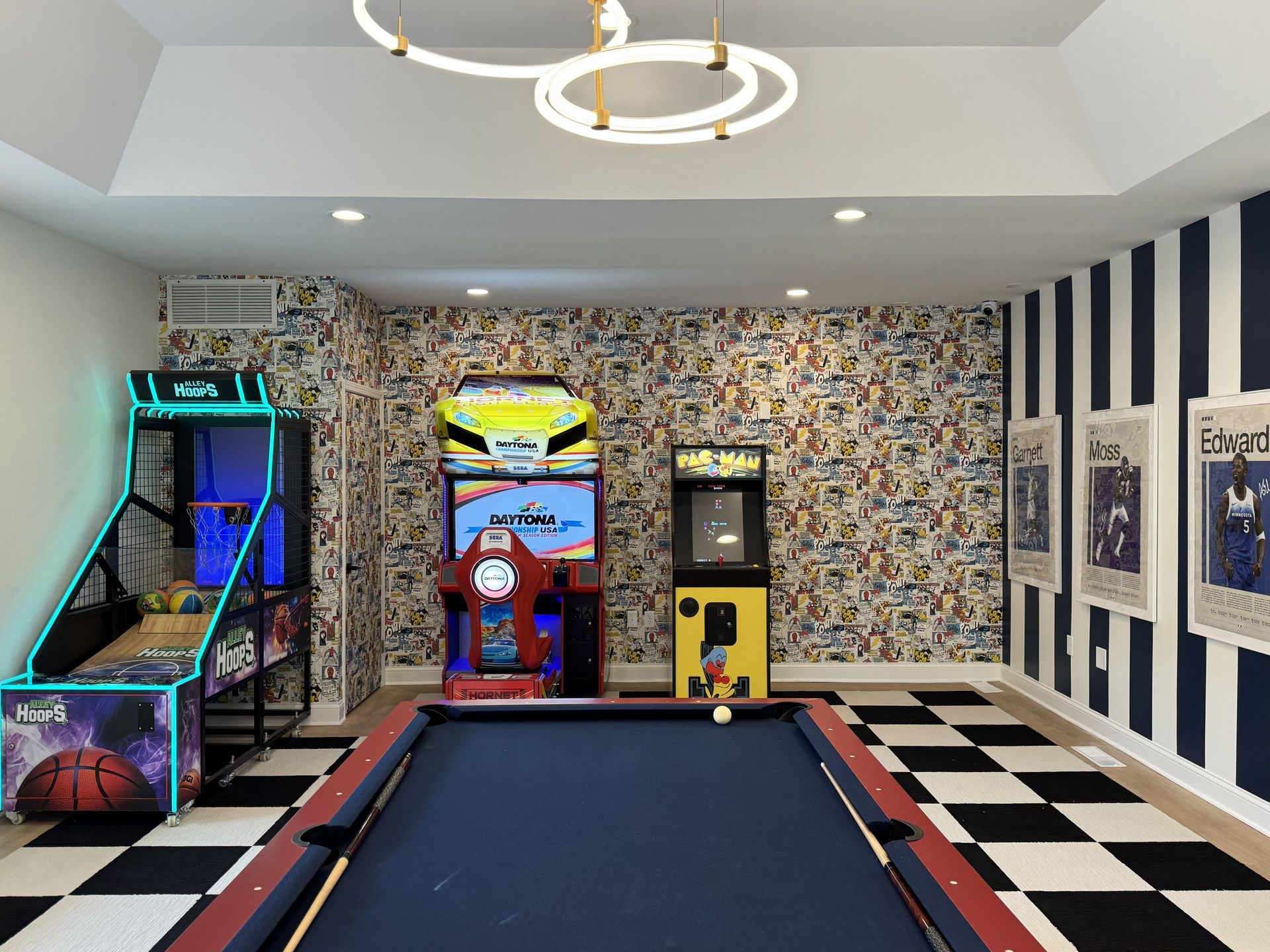A game room with a pool table, basketball arcade game, car racing game, arcade cabinet, and checkered floor.